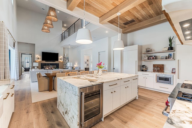 kitchen with a towering ceiling, white cabinetry, a center island, and wine cooler
