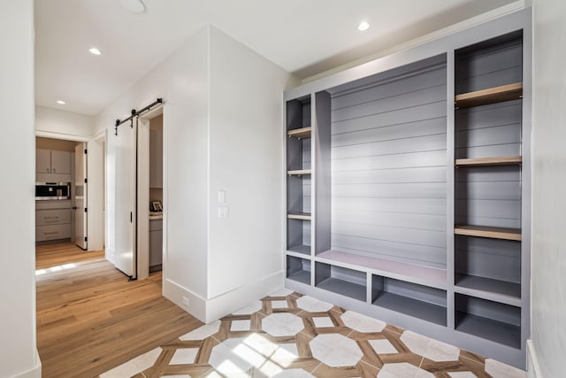 mudroom featuring baseboards, light wood finished floors, recessed lighting, and a barn door