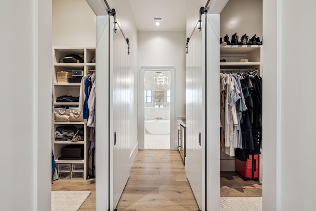 walk in closet featuring a barn door and light wood-style flooring