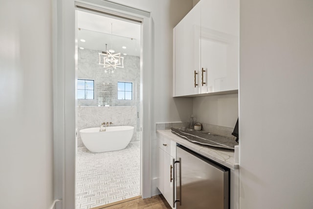 interior space featuring vanity, wood finished floors, a walk in shower, a freestanding bath, and a notable chandelier