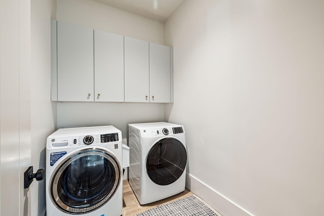washroom with baseboards, light wood-style flooring, cabinet space, and washing machine and clothes dryer