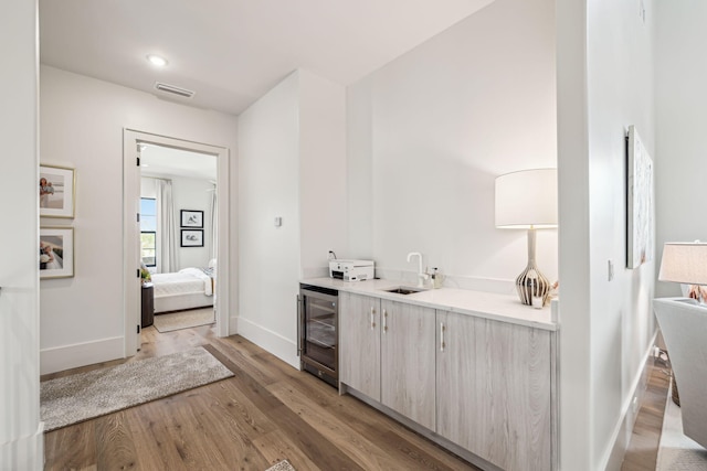 bathroom with visible vents, wine cooler, wood finished floors, baseboards, and connected bathroom