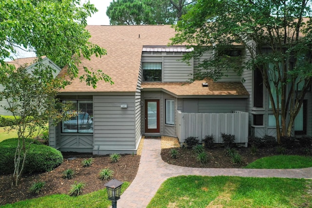 view of property with roof with shingles and fence