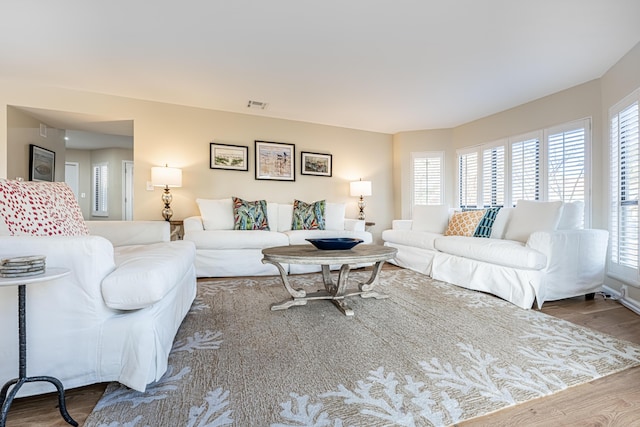 living room featuring visible vents, wood finished floors, and a healthy amount of sunlight