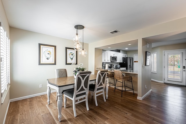 dining area with baseboards, visible vents, and dark wood finished floors