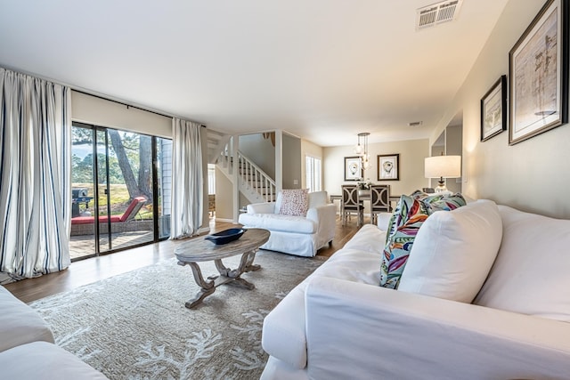 living area with plenty of natural light, stairs, wood finished floors, and visible vents