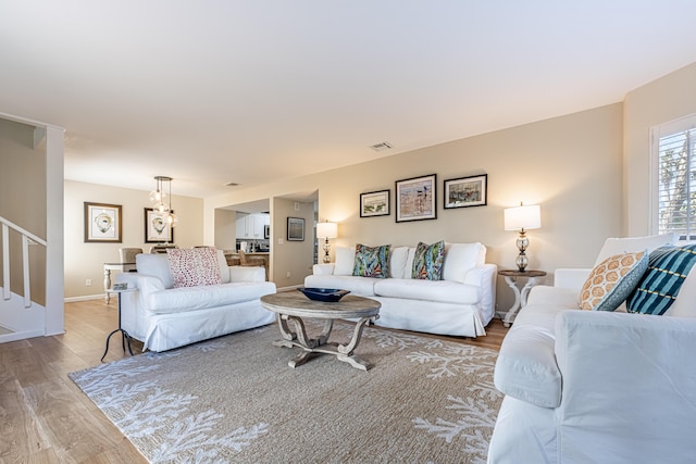 living area with baseboards, visible vents, light wood finished floors, and stairs