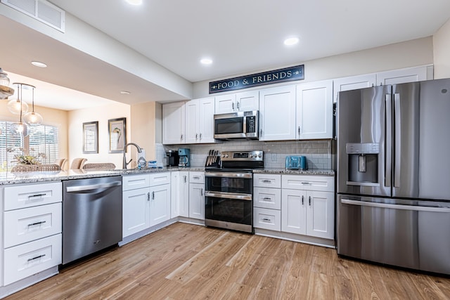 kitchen featuring visible vents, appliances with stainless steel finishes, a sink, a peninsula, and white cabinetry