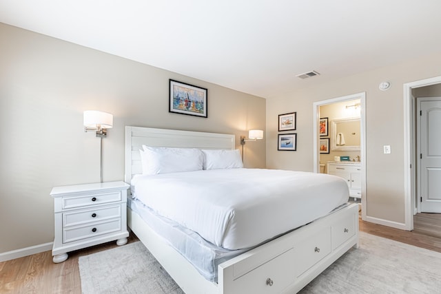 bedroom with baseboards, visible vents, ensuite bathroom, and light wood-style floors