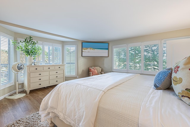 bedroom featuring baseboards, multiple windows, and wood finished floors