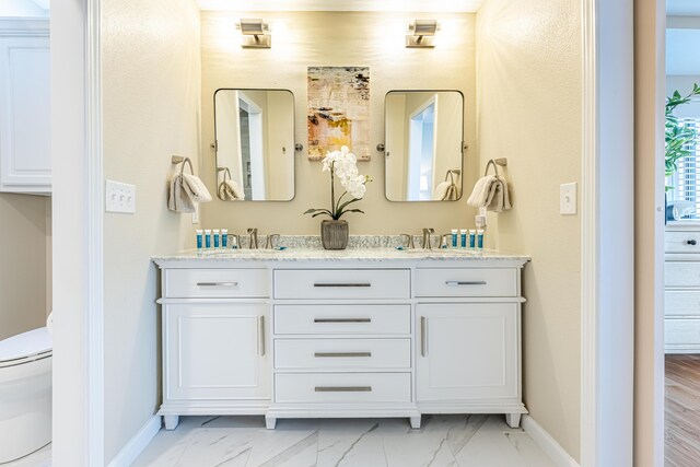 bathroom featuring baseboards, a sink, marble finish floor, and toilet