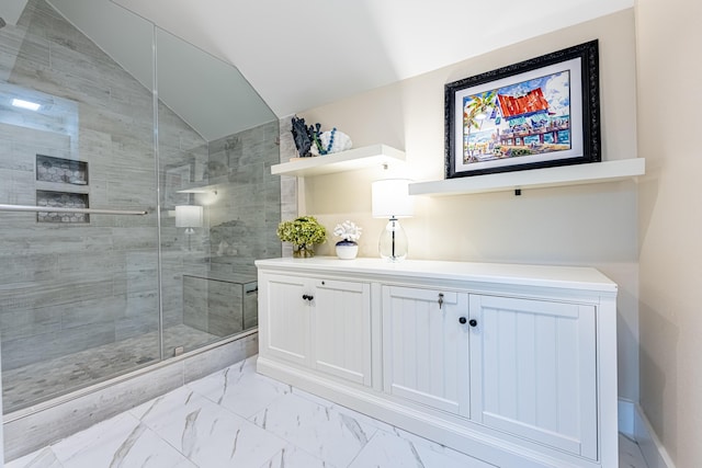 bathroom featuring vaulted ceiling, a shower stall, and marble finish floor