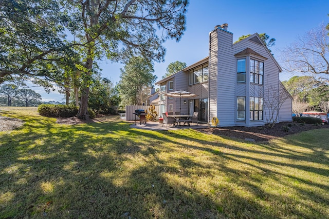 rear view of property with a patio, a chimney, and a yard
