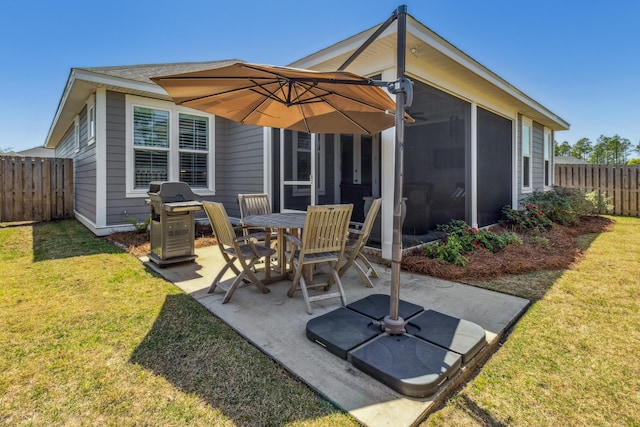 rear view of house with a sunroom, a patio area, and a lawn