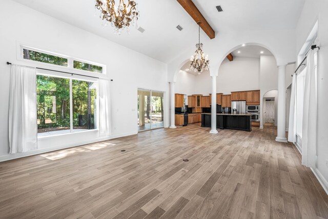 2928 Pine Valley Dr, Miramar Beach, FL 32550 - unfurnished living room featuring beamed ceiling, arched walkways, high vaulted ceiling, and a notable chandelier