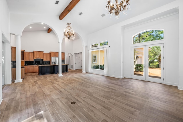 2928 Pine Valley Dr, Miramar Beach, FL 32550 - unfurnished living room with beam ceiling, arched walkways, high vaulted ceiling, a chandelier, and visible vents