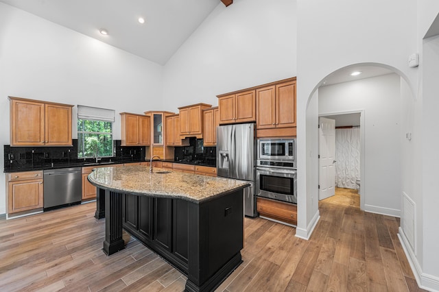 2928 Pine Valley Dr, Miramar Beach, FL 32550 - kitchen featuring arched walkways, light stone countertops, a sink, high vaulted ceiling, and stainless steel appliances
