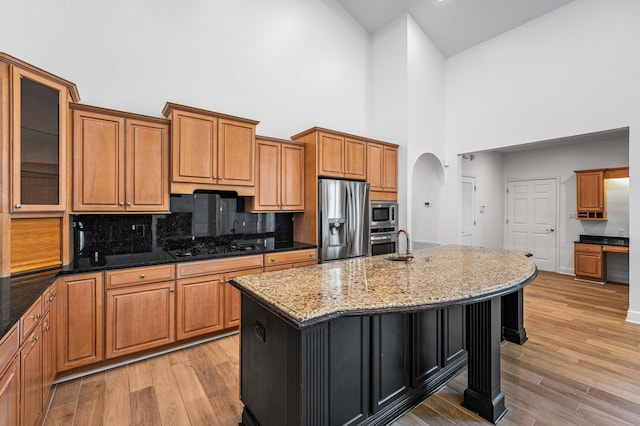 2928 Pine Valley Dr, Miramar Beach, FL 32550 - kitchen featuring arched walkways, light wood-style flooring, dark stone countertops, stainless steel appliances, and a towering ceiling