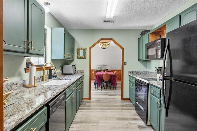 612 Moss Dr, Crestview, FL 32536 - kitchen with visible vents, a sink, light wood-style flooring, black appliances, and green cabinets