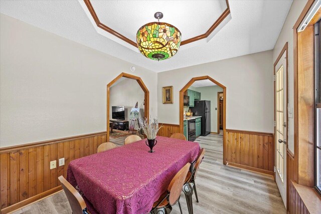 612 Moss Dr, Crestview, FL 32536 - dining space with a textured ceiling, arched walkways, a wainscoted wall, light wood finished floors, and wooden walls