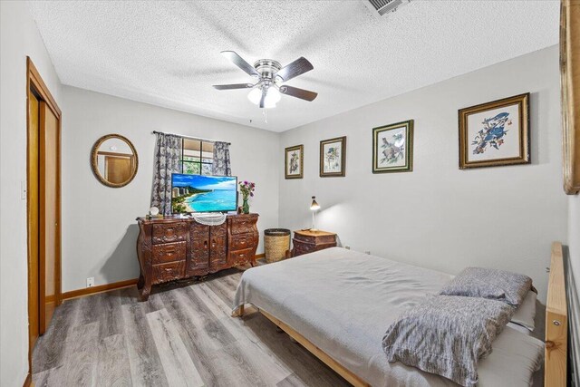 612 Moss Dr, Crestview, FL 32536 - bedroom with visible vents, a ceiling fan, a textured ceiling, and wood finished floors