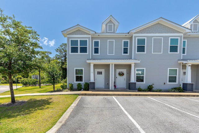 multi unit property with uncovered parking, a front lawn, and metal roof