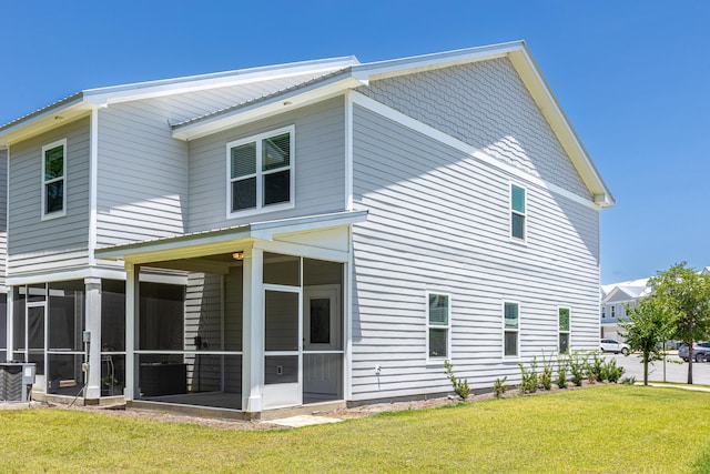 back of property featuring a sunroom and a lawn