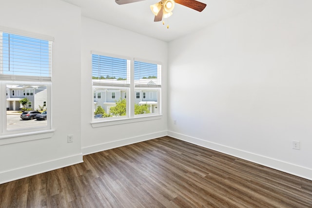 empty room with a ceiling fan, dark wood finished floors, and baseboards