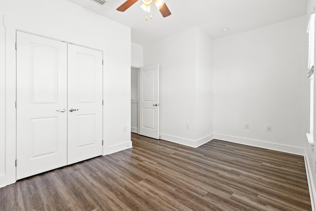 unfurnished bedroom with dark wood-style floors, baseboards, a closet, and a ceiling fan