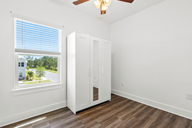 unfurnished bedroom with dark wood-style floors, baseboards, a closet, and a ceiling fan