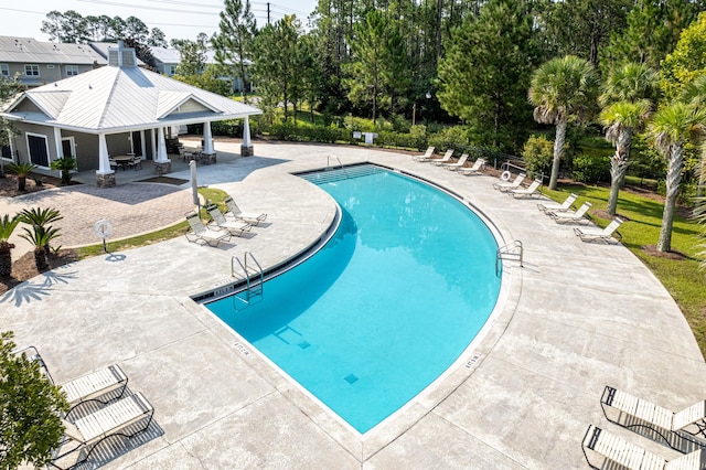 community pool featuring a patio area and view of scattered trees