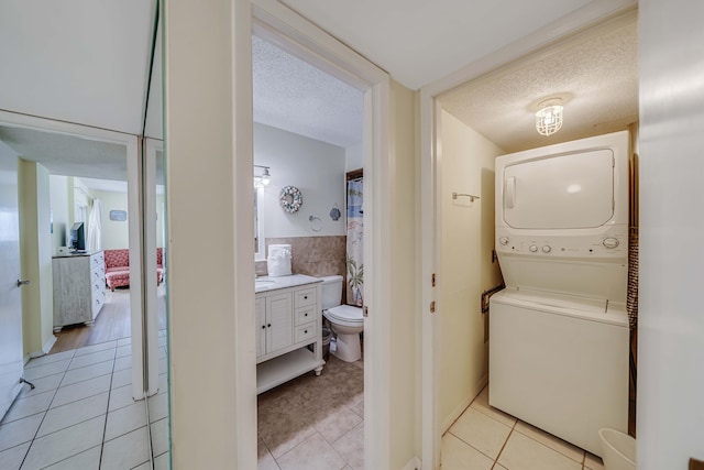 5801 Thomas Dr Unit 620, Panama City Beach, FL 32408 - clothes washing area with a textured ceiling, stacked washer / drying machine, light tile patterned flooring, and laundry area