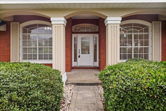 entrance to property featuring brick siding and covered porch