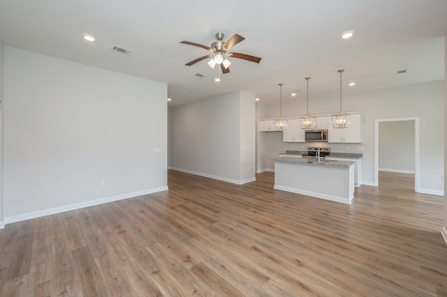 unfurnished living room with a ceiling fan, baseboards, light wood finished floors, and visible vents