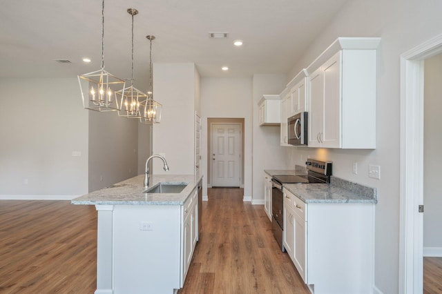 kitchen featuring a sink, stainless steel appliances, a kitchen island with sink, light wood-style flooring, and white cabinetry
