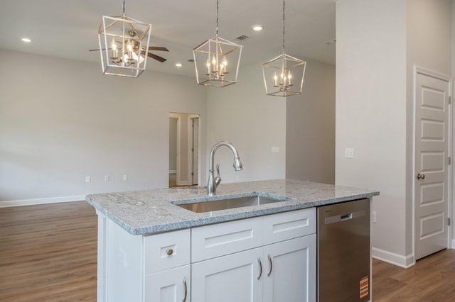 kitchen with an inviting chandelier, wood finished floors, a sink, stainless steel dishwasher, and baseboards