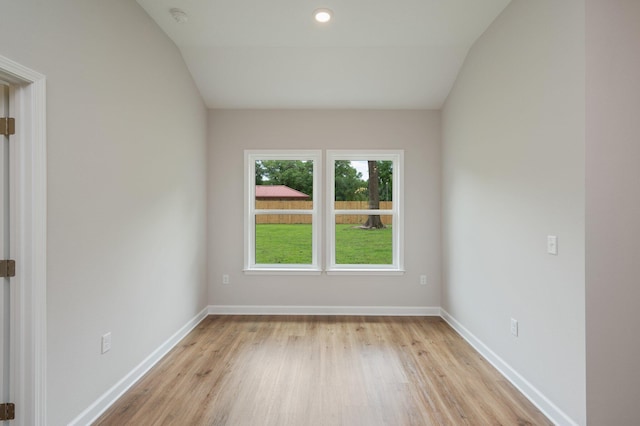 spare room with baseboards, lofted ceiling, and light wood finished floors