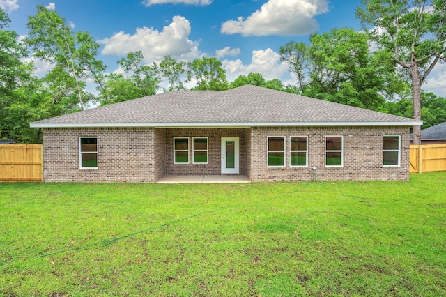 back of house with a patio, a lawn, a shingled roof, a fenced backyard, and brick siding