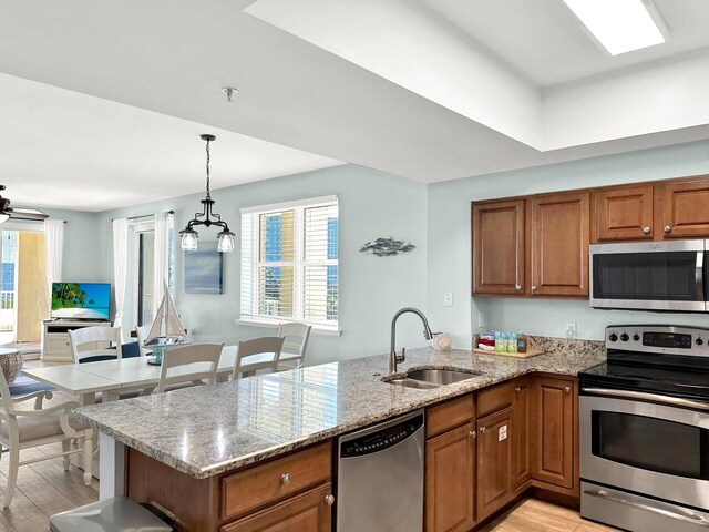 112 Seascape Dr Unit 310, Miramar Beach, FL 32550 - kitchen with appliances with stainless steel finishes, a sink, brown cabinets, a peninsula, and light wood-style floors