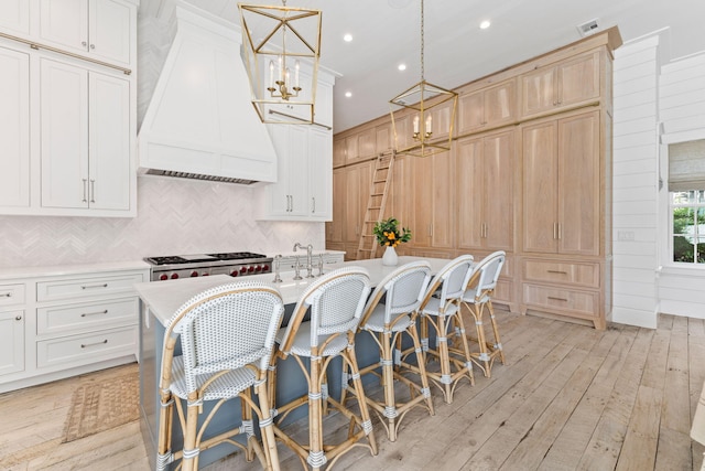 28 Rainer Ln, Inlet Beach, FL 32461 - kitchen featuring premium range hood, light wood-type flooring, decorative backsplash, light countertops, and a notable chandelier