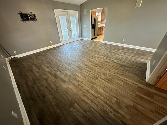 unfurnished living room featuring french doors, baseboards, wood finished floors, lofted ceiling, and visible vents