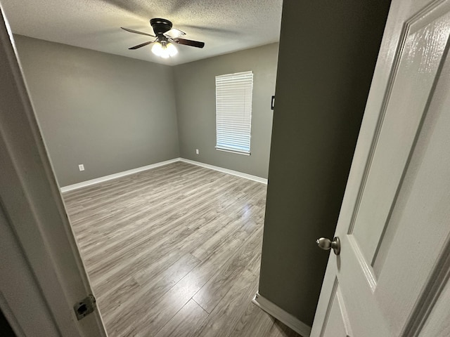 unfurnished bedroom with baseboards, a ceiling fan, a textured ceiling, and wood finished floors