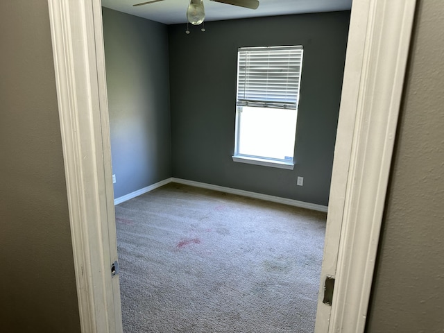 carpeted empty room featuring baseboards and ceiling fan