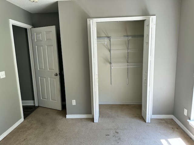 unfurnished bedroom featuring a closet, baseboards, and carpet floors
