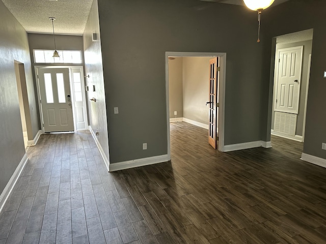 foyer with visible vents, a towering ceiling, baseboards, dark wood-style floors, and a textured ceiling