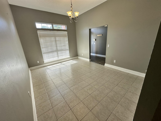 tiled spare room featuring baseboards and a notable chandelier