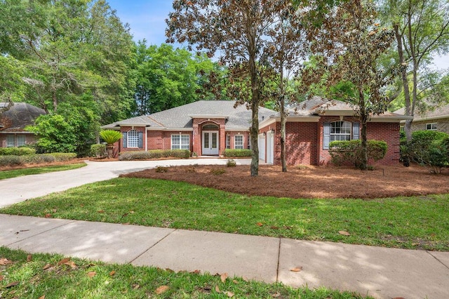 ranch-style home with concrete driveway, a garage, french doors, a front lawn, and brick siding