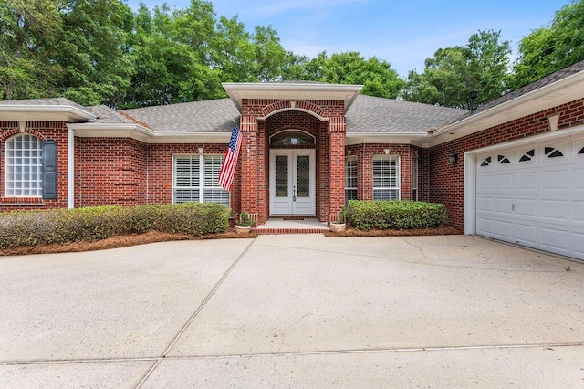single story home featuring brick siding, roof with shingles, concrete driveway, french doors, and an attached garage
