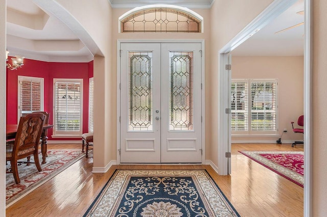 entrance foyer with french doors, plenty of natural light, wood finished floors, and crown molding