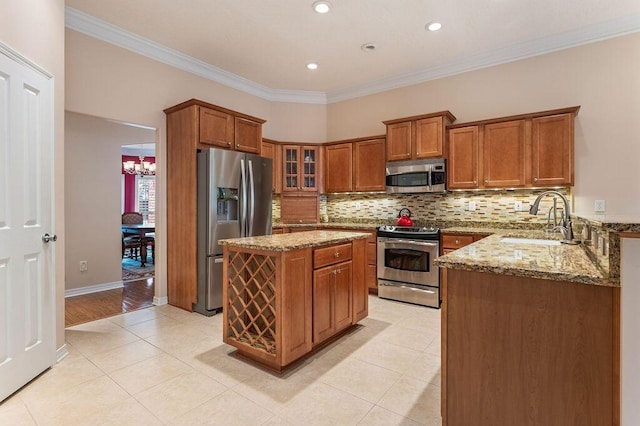 kitchen with stainless steel appliances, brown cabinetry, light stone countertops, backsplash, and crown molding